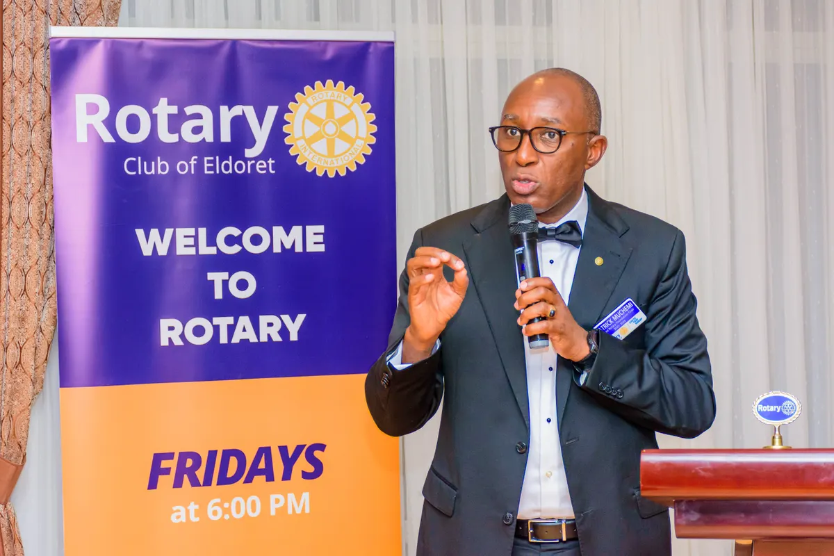 A club member addressing a weekly meeting beside the club's Welcome to Rotary banner